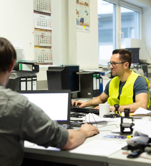 Büroarbeit - Mehrere Mitarbeiter arbeiten am Schreibtisch vor ihren PC's